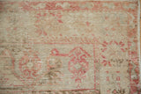 Distressed vintage Oushak rug texture, showing worn pile, visible foundation, and muted blush.