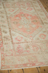 Distressed vintage Oushak runner showcasing pale blush and neutral floral patterns with visible pile wear.