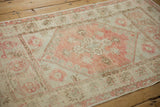 Distressed Oushak rug with worn dusty blush quatrefoil medallion and ivory floral patterns.