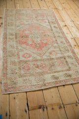 Distressed Oushak rug corner, dusty blush floral main and meandering vine borders.