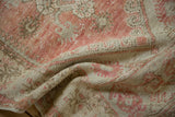 Faded blush and ivory tones with visible wear to the knot heads and foundation.