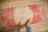 Personal view of a distressed Oushak rug's worn texture and cherry red and ivory tones.