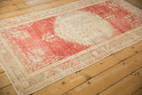 Angled view of a distressed Oushak rug highlighting its cherry red field and time-softened ivory medallion.