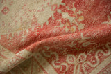 A soft fold highlights the worn, hand-knotted texture of a cherry red and ivory Oushak rug.