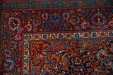A collector Persian Kashan corner with cloudband motifs in ruby red, navy, and sapphire blue.