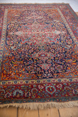 Intricate sprawling vines and palmettes in gem-like colors on an antique Persian Kashan rug.
