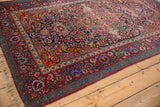 Angled view of an antique Kashan's intricate borders, rich with ruby, navy, and tangerine palmettes.