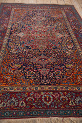 Low-angle perspective across the antique Kashan's intricate field of sprawling vines and palmettes.