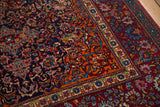 Vivid gem-like tones in the scrolling vines and cloudband motifs of an antique Kashan rug corner.