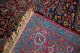 Corner view of an antique Kashan contrasting the ruby red pile with the detailed reverse weave.