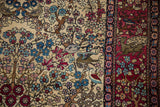 Antique Isfahan rug detail showing pictorial birds and a leopard in the cochineal red border.