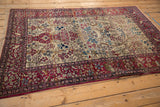 Angled view of an antique Isfahan rug, displaying its intricate Tree of Life pattern and animal motifs.
