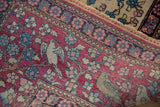 Pictorial bird and floral motifs on the cochineal red border of an antique Isfahan rug.