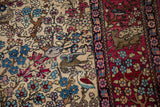 A fine Isfahan rug's ivory field with birds beside the pictorial cochineal red border with animals.