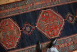 Antique Bijar rug border with meandering vines and red stepped hexagonal medallion on navy.