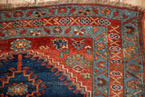 Hand-knotted Antique Bijar rug corner, featuring madder red field and dusty teal geometric borders with short fringe.