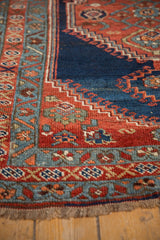 Antique Bijar rug corner with geometric and floral borders, navy, red, teal, showing fringe.