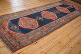 Antique Bijar runner corner with tiered madder root red borders, geometric teal motifs, and hand-knotted fringe.