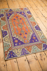 Vibrant terracotta and aubergine geometric patterns on a small distressed Turkish Oushak rug.