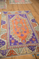 Angled view of a vintage distressed Oushak rug with vibrant terracotta and aubergine geometric motifs.
