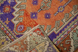 Folded corner of a vintage Oushak rug shows its hand-knotted back and colorful terracotta pile.