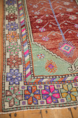 Distressed Oushak rug detail showing vibrant floral border and tree of life motif.