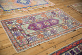Distressed vintage Oushak rug showing ornate borders in tangerine, aubergine, and seafoam green.