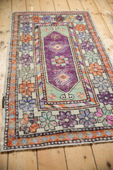 Distressed Oushak runner's aubergine field, mint green finned floral cartouche, geometric borders.