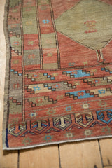 Distressed Oushak rug corner, showing terra cotta panels with starbursts and sky blue highlights.