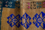 Side cord and camel wool texture of a distressed Kars rug with vibrant blue motifs.
