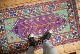 A person's view looking down at a distressed vintage Oushak runner's colorful design.