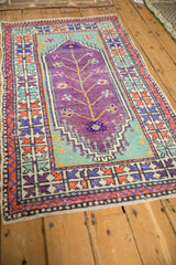 Angled view of a vintage Oushak runner's purple tree of life design and colorful geometric borders.