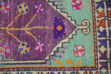 Stylized rams horn and arrowed main border in aubergine and mint green.