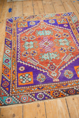 Distressed Oushak rug detail showing vibrant violet border and geometric turquoise motifs.