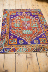 Distressed Oushak rug fringed end, showing violet, rust, turquoise geometric patterns.