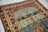 Angled view of an antique Kermanshah's Tree of Life on a powder blue field alongside its intricate floral border.