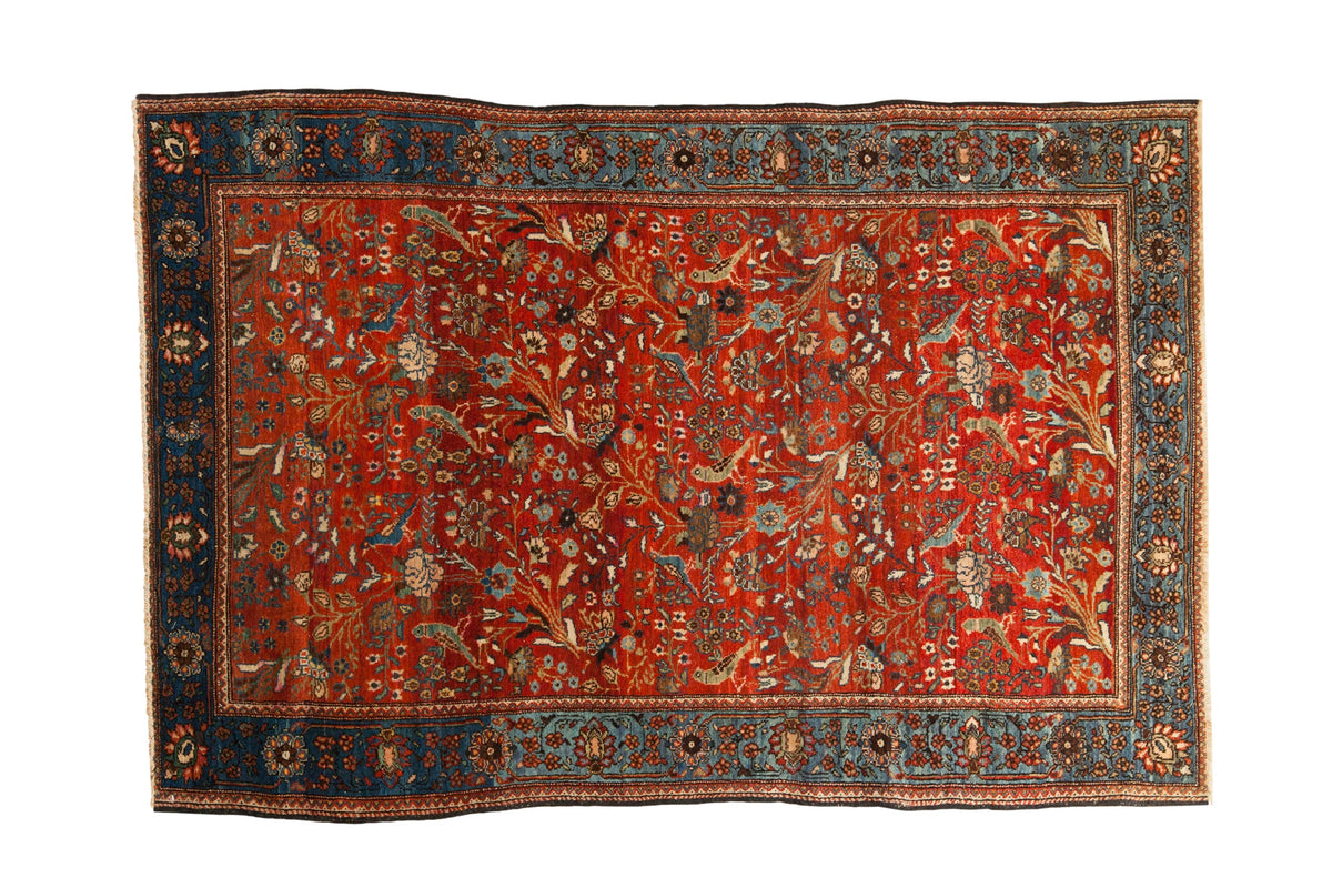 Antique Farahan Sarouk rug with a repeating forest scene of birds and vines in vivid red and sapphire blue.