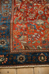 Antique Farahan Sarouk rug corner showing a ruby red floral field against a deep blue border.