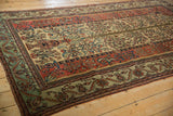 Antique Fereghan carpet corner showing the Tree of Life vase and wide jade green floral border.