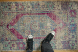Worn texture of distressed Oushak rug showing faded eggplant, blue, and beige geometric motifs.