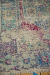 Close-up of distressed vintage Oushak rug, worn pile revealing foundation with muted blue, eggplant hues.