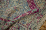 Folded vintage Distressed Oushak rug pile revealing worn texture with eggplant, blue, and beige.