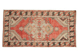 Vintage Oushak rug runner with a distressed medallion in dusty cherry red, ivory, and charcoal accents.