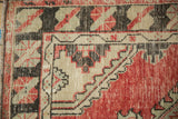 Worn texture of a vintage Oushak corner showing charcoal serpent and vine motif borders.