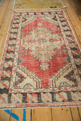 Angled view of a distressed Oushak runner with a serrated medallion in red and charcoal.