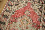 Worn, hand-knotted texture on a vintage Oushak rug showing a charcoal serpent border motif.