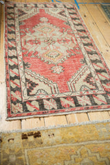 Angled view of a distressed Oushak runner showing its full length and cherry red geometric pattern.