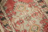 Detailed view of distressed hand-knotted pile with serrated motifs in cherry red and saffron.