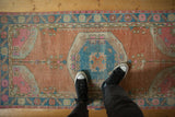 Distressed Oushak rug runner with sandalwood, blue, and pink tones underfoot.