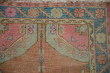 Hand-knotted vintage distressed Oushak rug corner with pink, blue, sandalwood floral patterns.